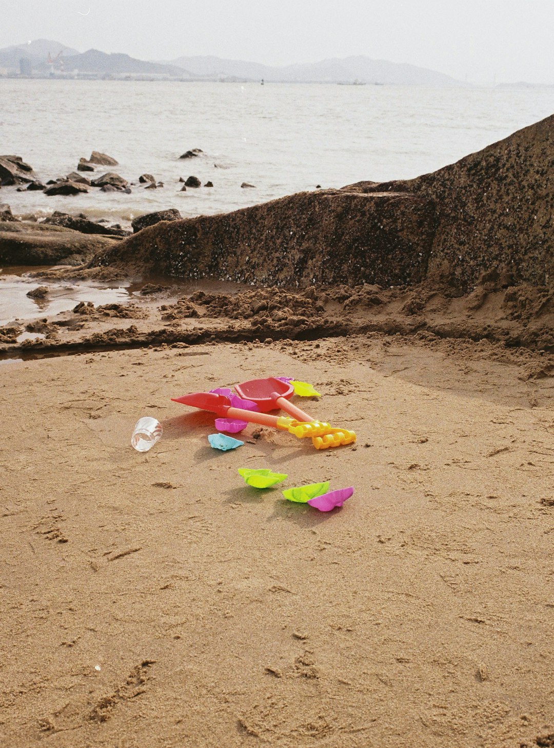 pink and white plastic toy on brown sand near body of water during daytime