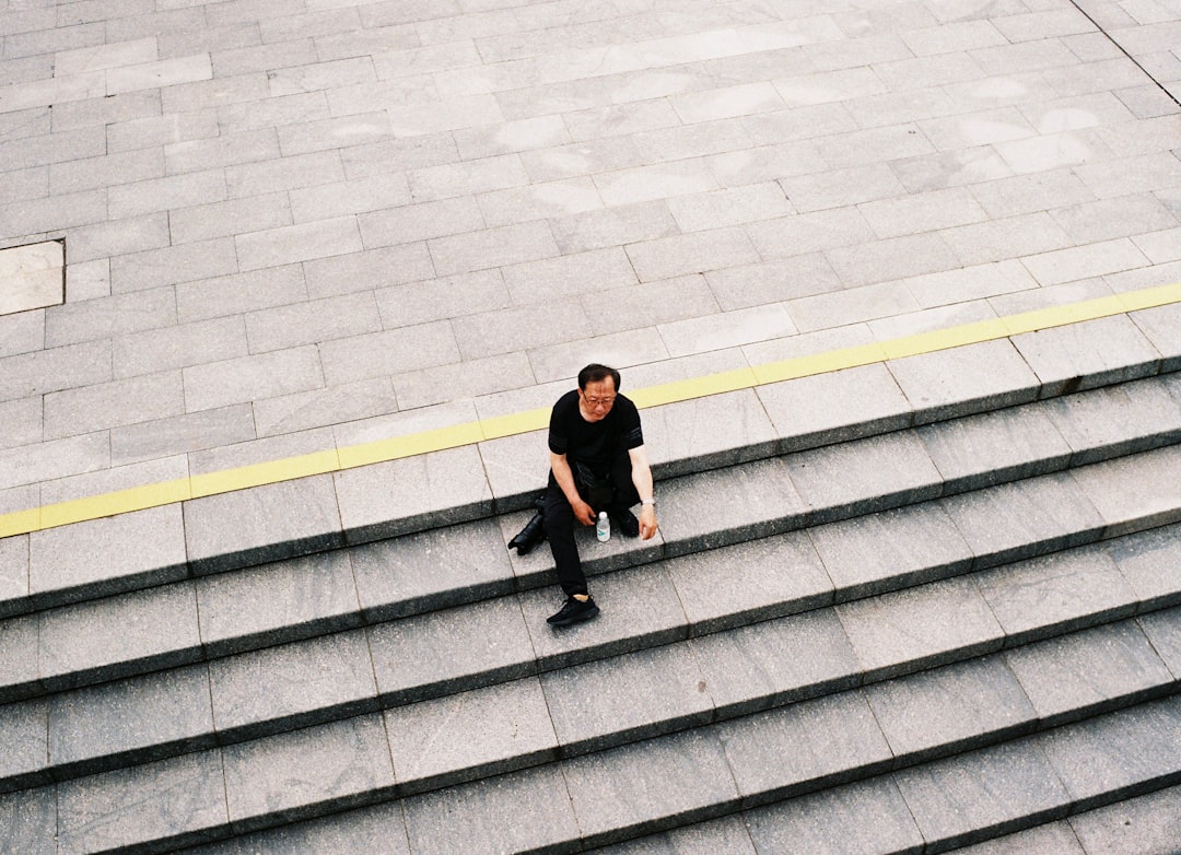 man in black shirt and black pants sitting on gray concrete stairs