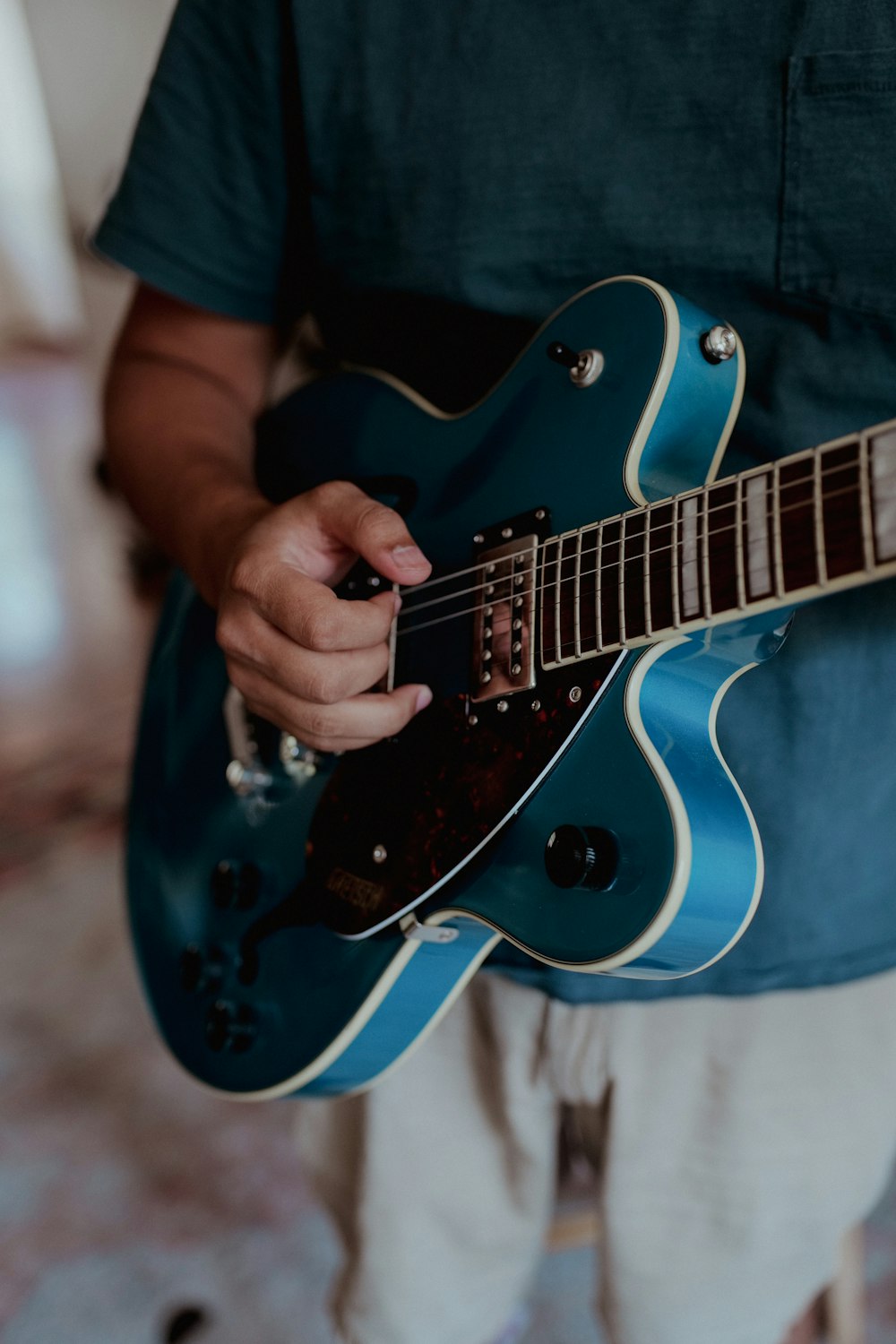 Person spielt blau-weiße Stratocaster E-Gitarre
