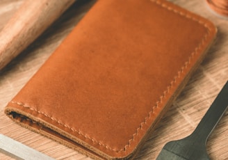 a leather wallet, a comb, thread, and scissors on a table