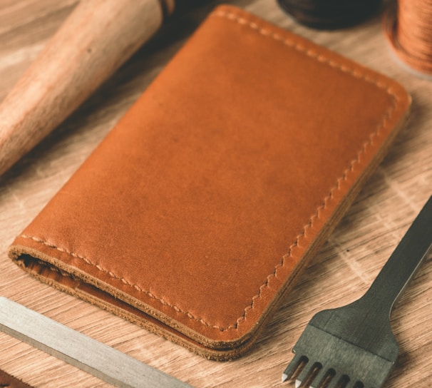 a leather wallet, a comb, thread, and scissors on a table