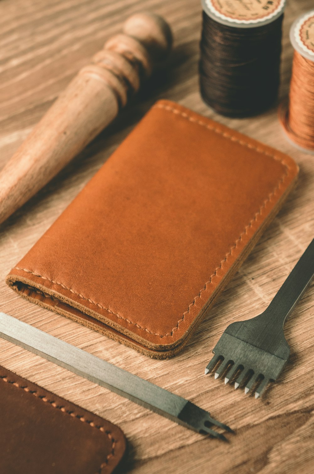 a leather wallet, a comb, thread, and scissors on a table