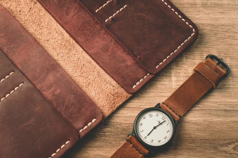 Un reloj sentado junto a una billetera en una mesa