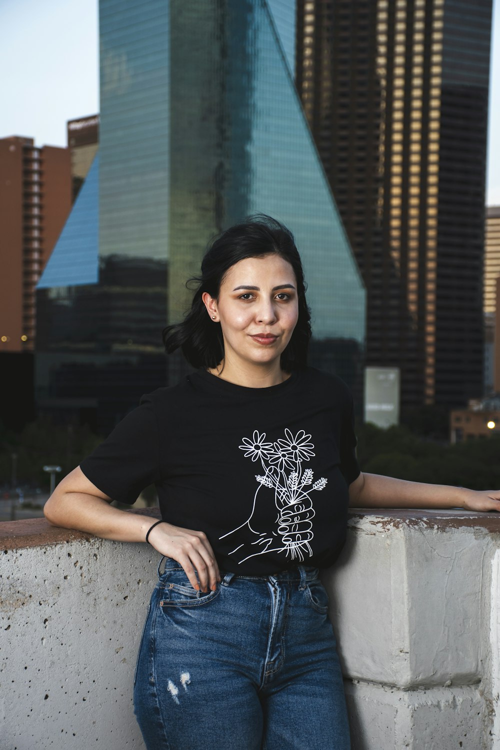 woman in black crew neck t-shirt and blue denim jeans sitting on concrete bench