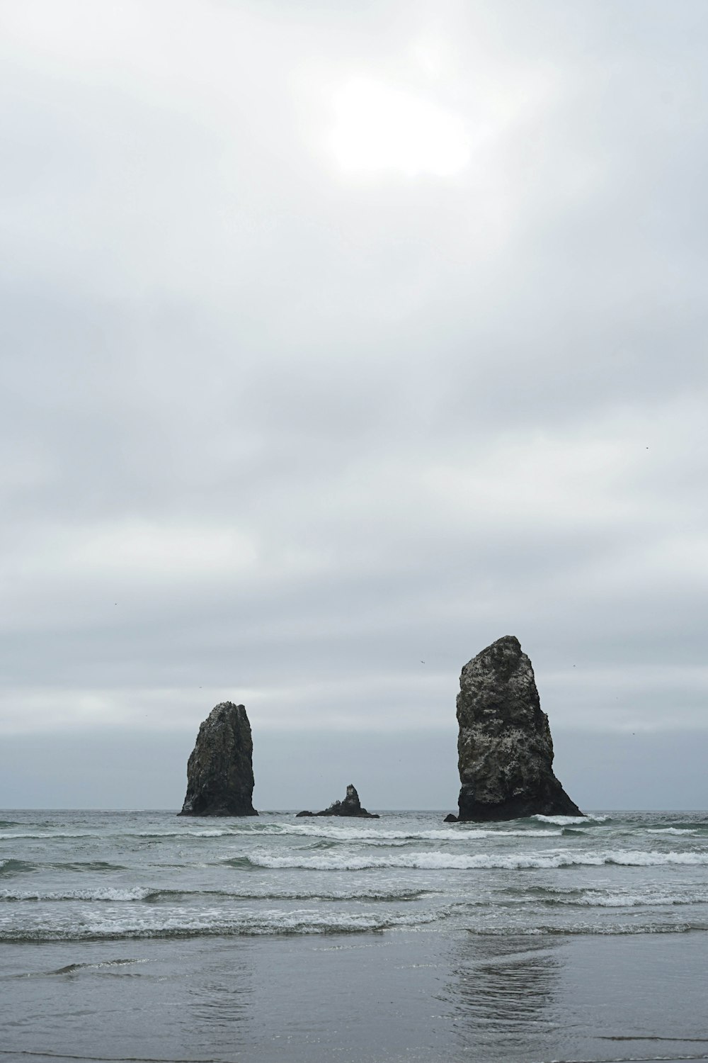 Formación de roca marrón en el mar bajo nubes blancas durante el día