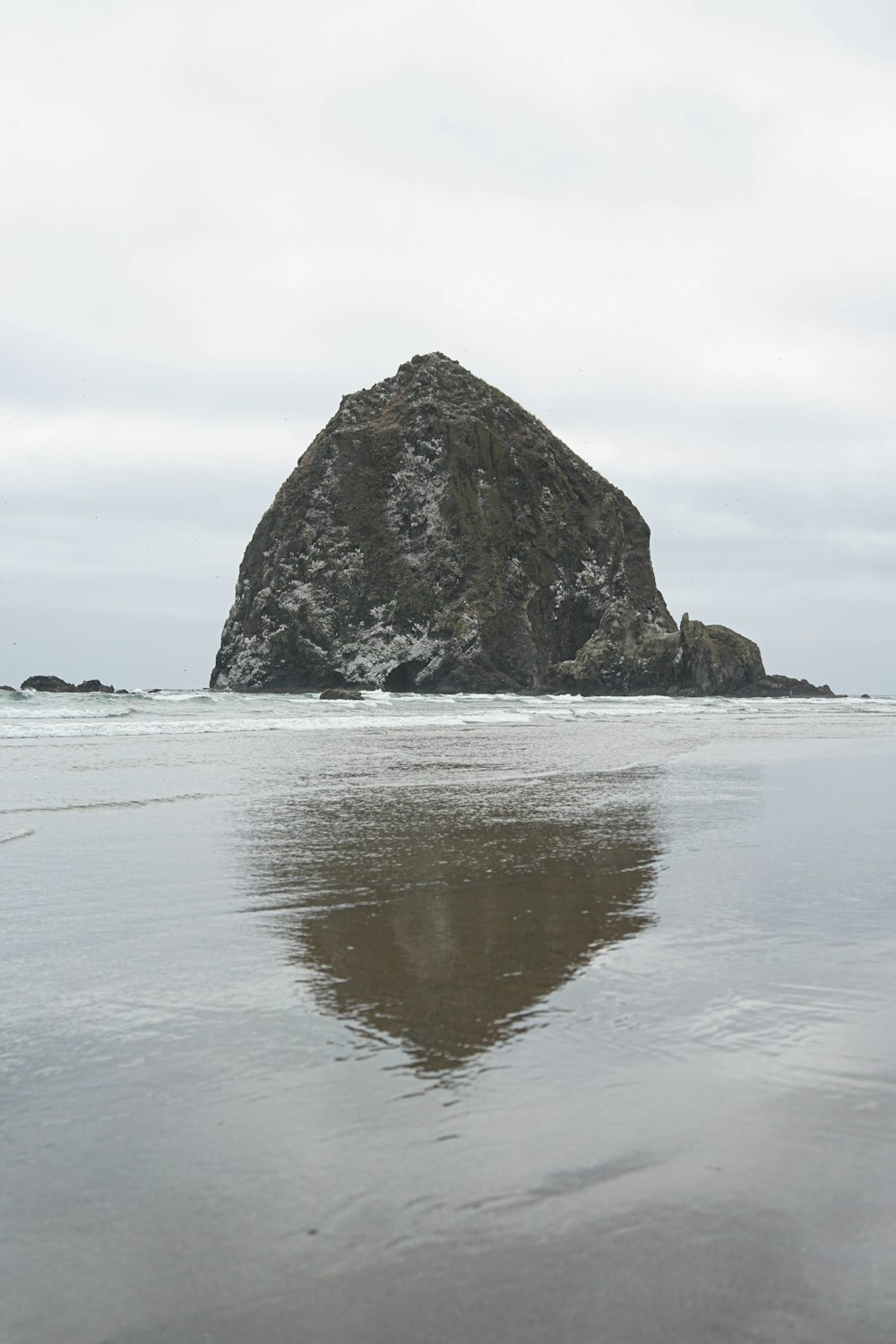 a large rock sitting on top of a beach next to the ocean