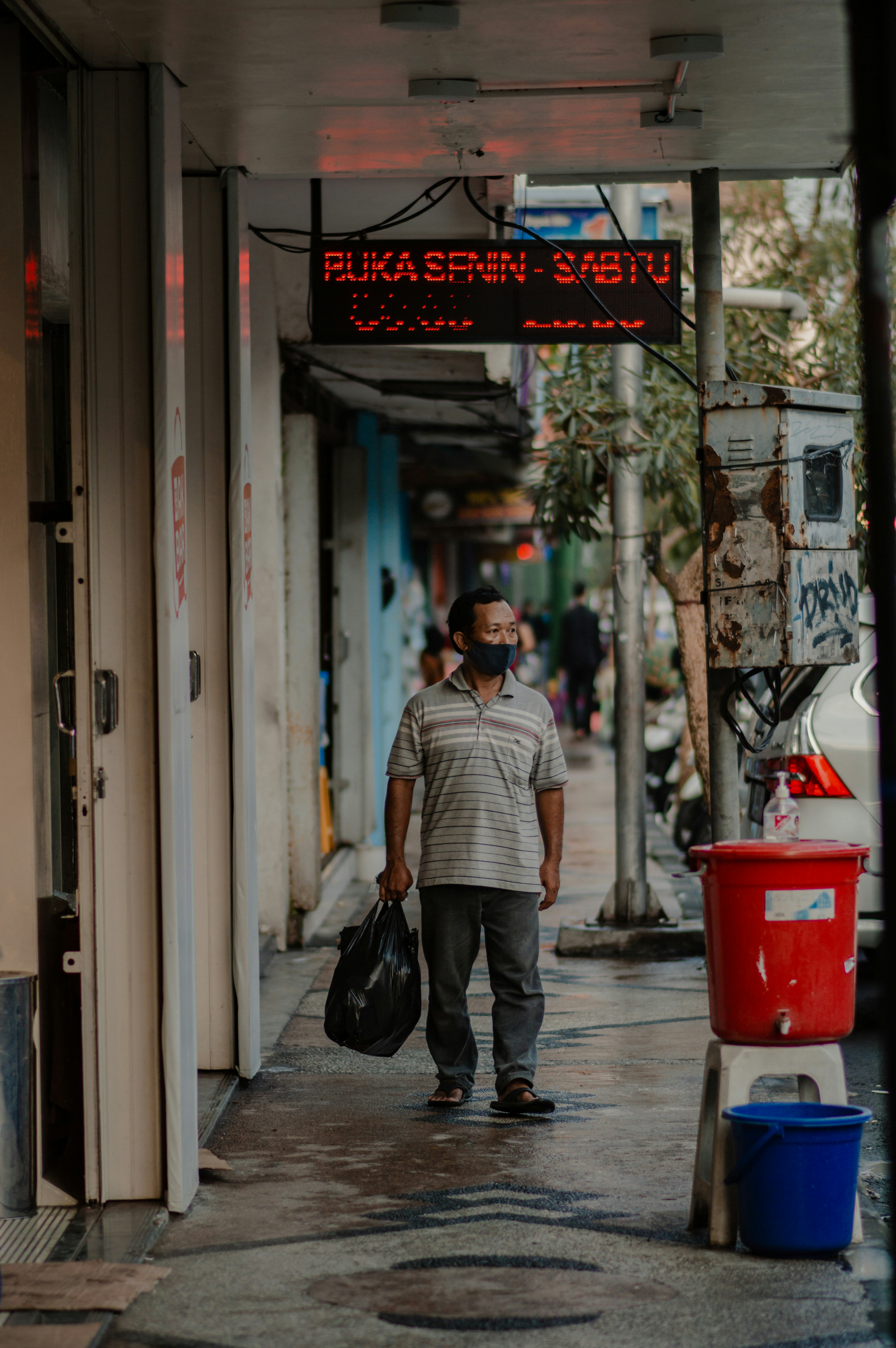Seorang pria berjalan di jalan sambil memegang tas