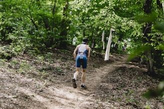 a man walking down a dirt path in the woods