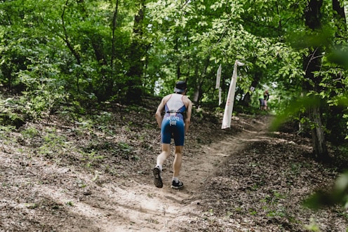 a man walking down a dirt path in the woods