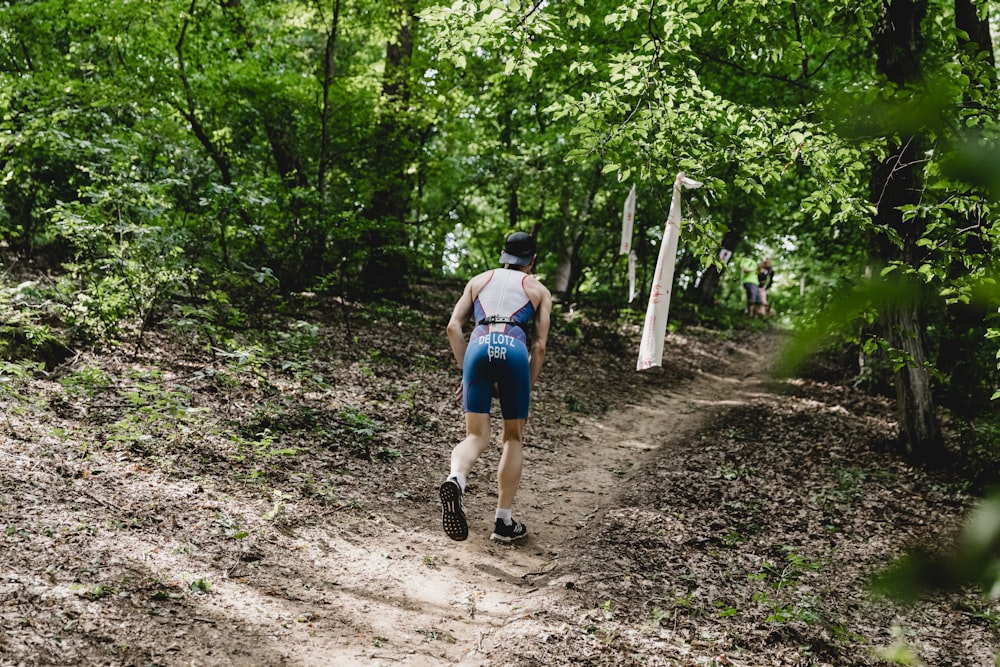 a man walking down a dirt path in the woods