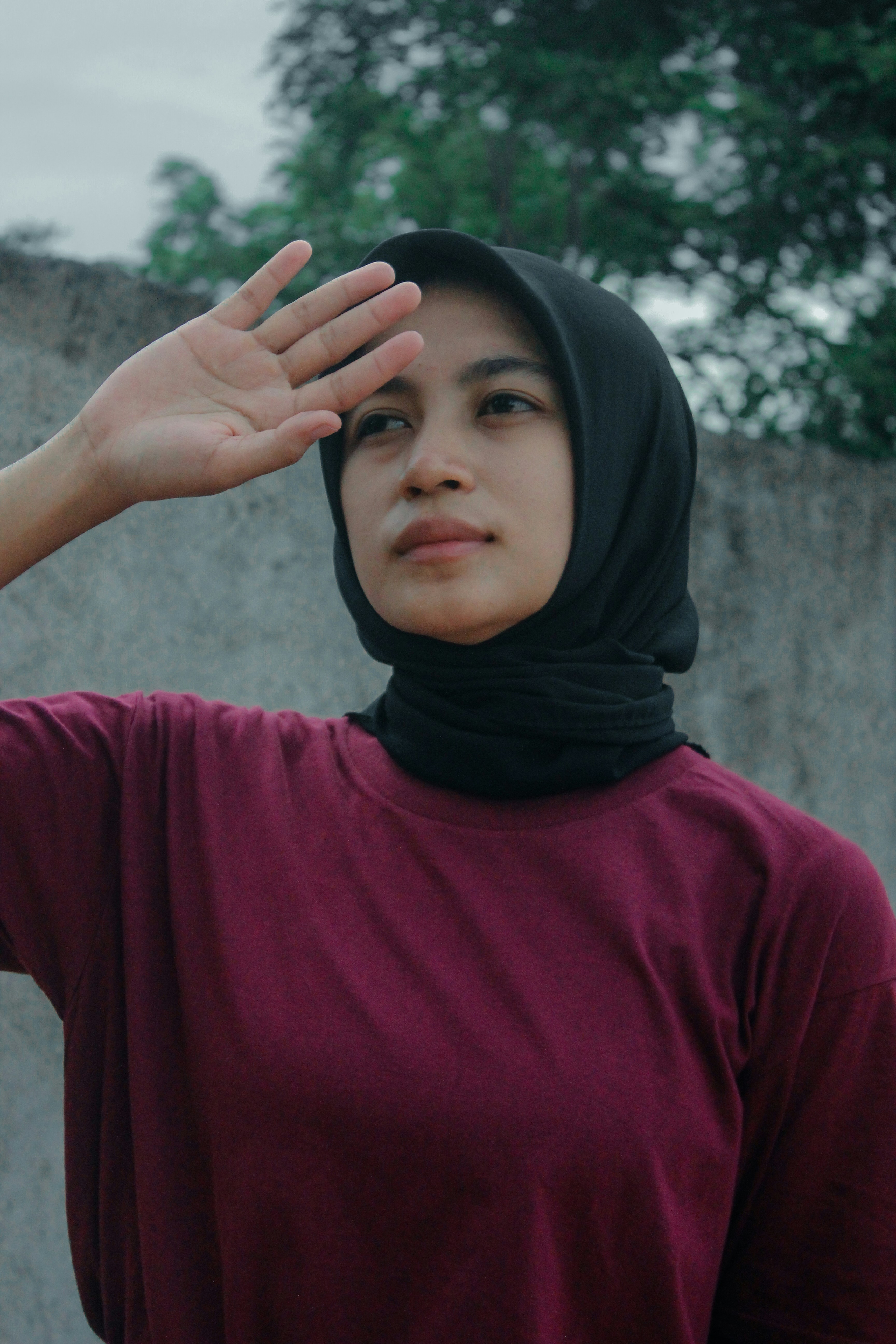 Seorang wanita dengan kemeja merah marun mengangkat tangannya