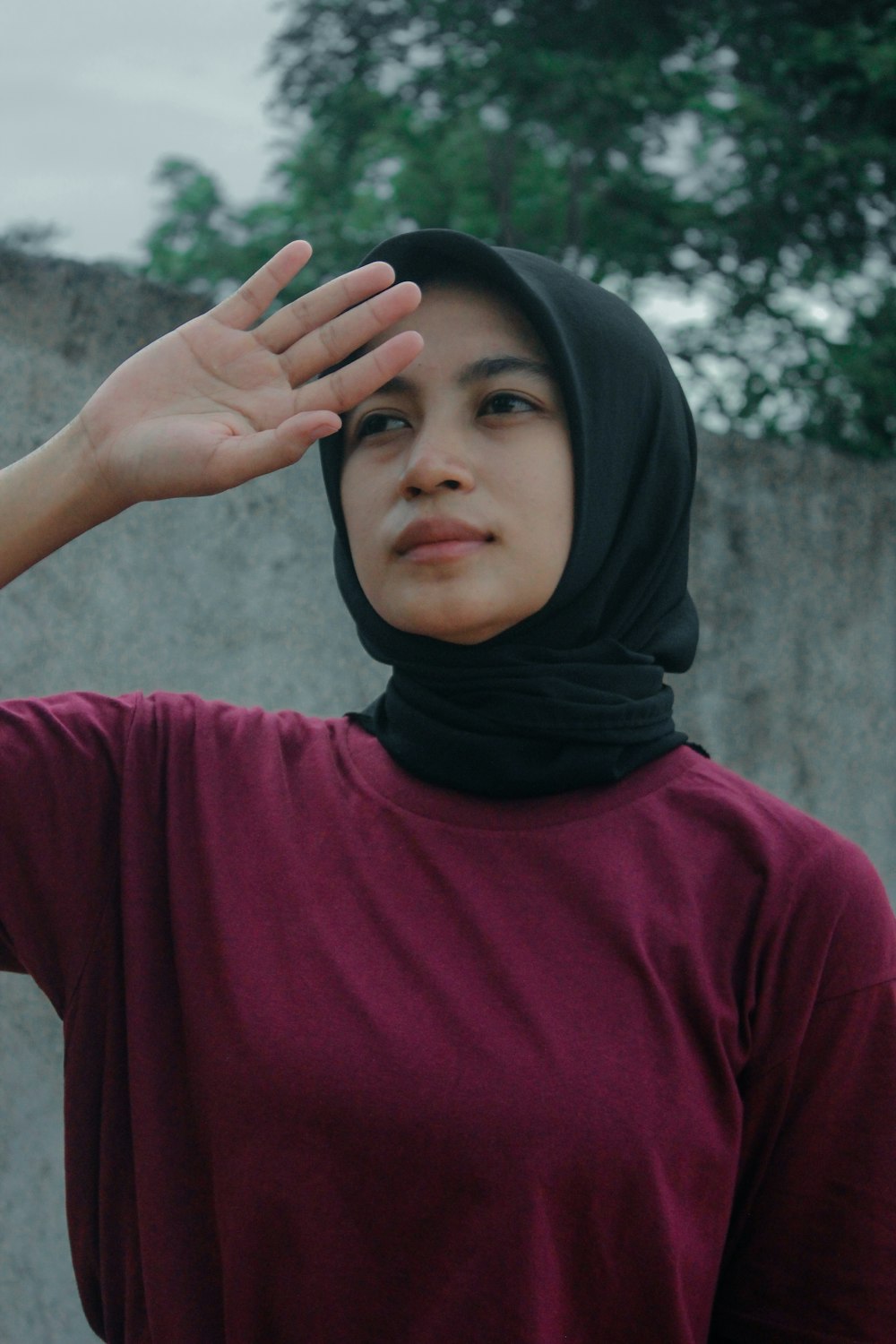 a woman in a maroon shirt is holding her hand up