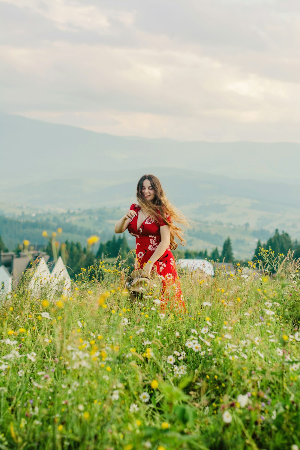 woman in red and white floral dress standing on green grass field during daytime