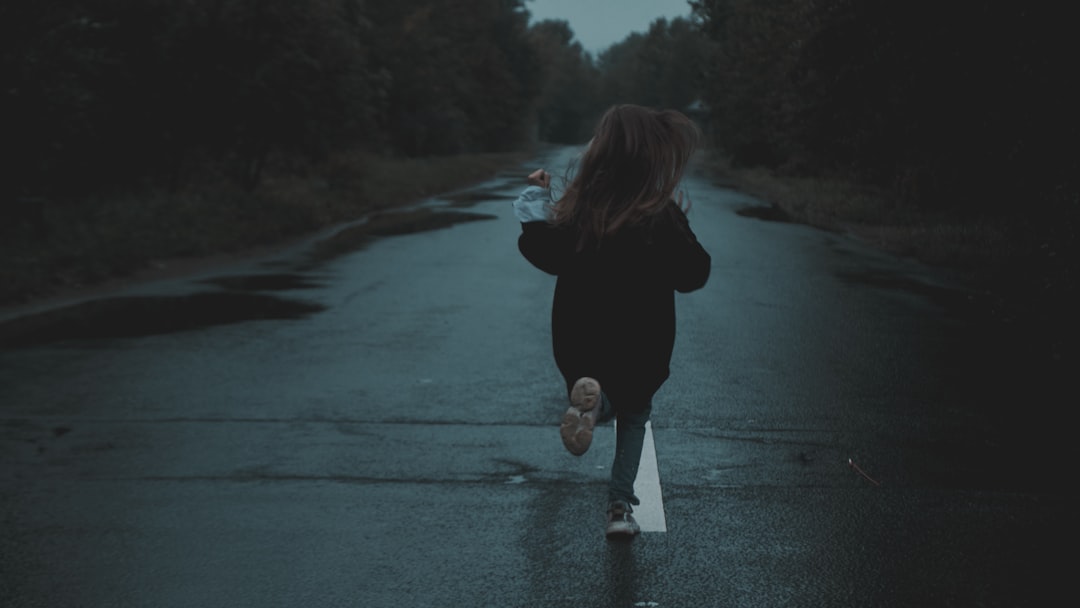 woman in black jacket and white pants walking on road during daytime