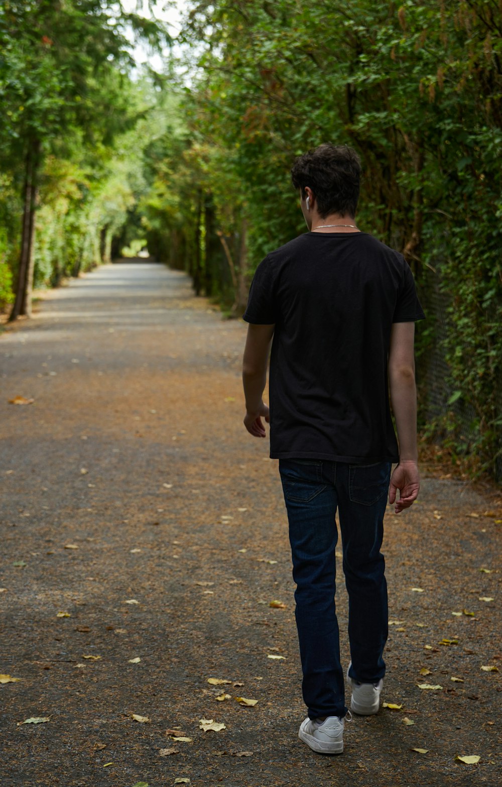 a man is walking down a tree lined road