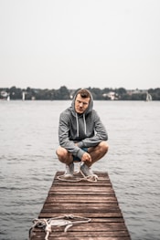 a man sitting on a dock tying his shoes