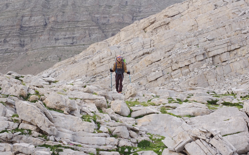 woman in black jacket and black pants walking on rocky mountain during daytime