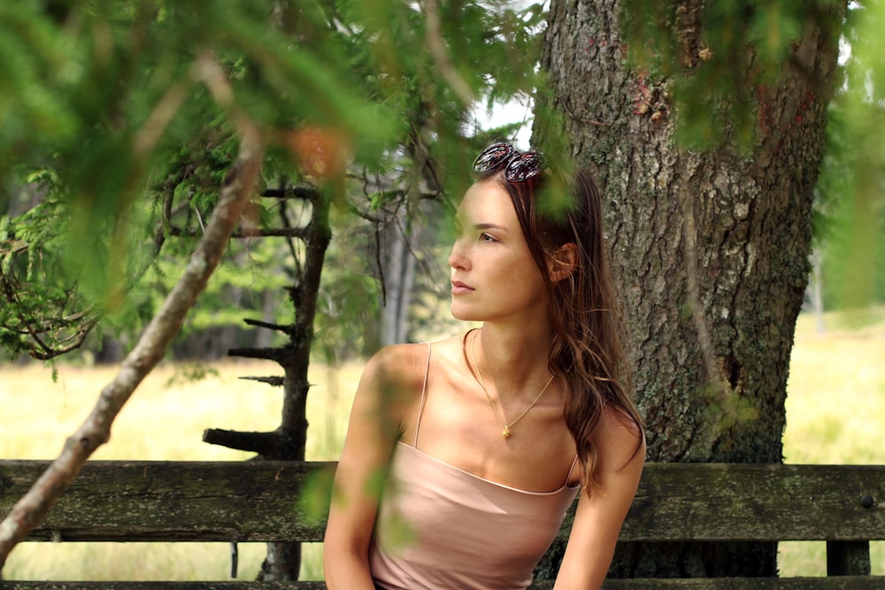 woman in beige tube dress leaning on tree