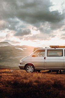 white suv on brown grass field near mountain during daytime