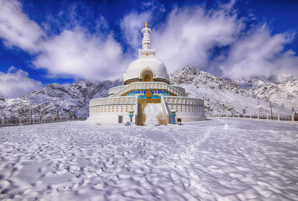 white and yellow concrete building on snow covered ground under white clouds and blue sky during