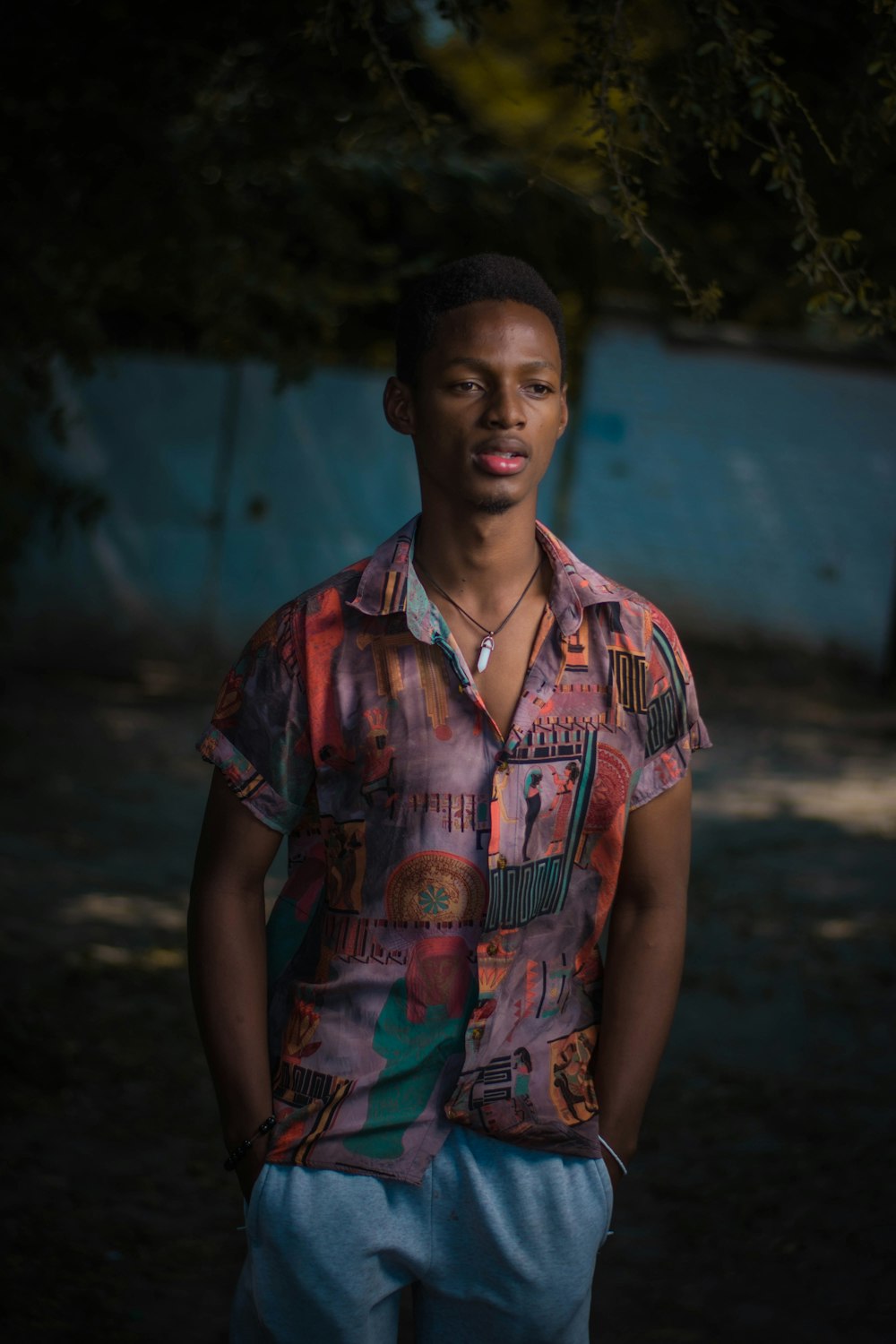 man in red blue and green floral button up shirt standing on brown soil during daytime