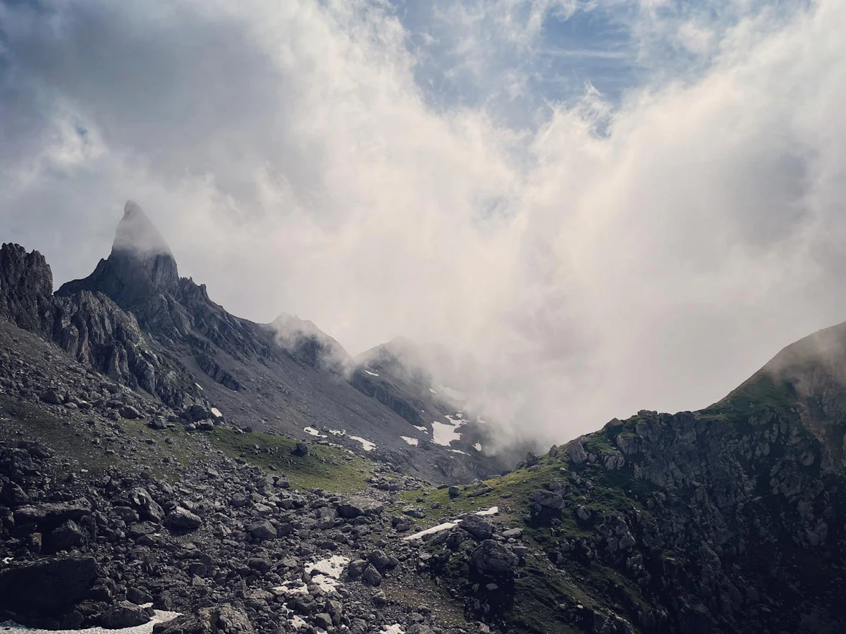 A rock pinnacle and scree slopes in the Beaufortain, half hidden by cloud