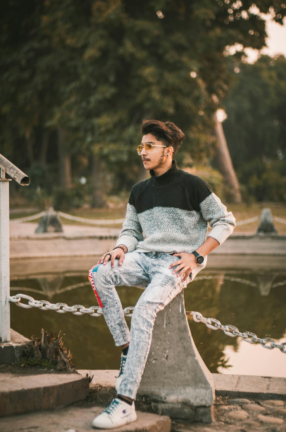 woman in gray and black sweater and blue denim jeans sitting on brown wooden fence during