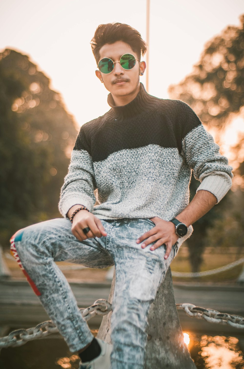 woman in gray sweater and blue denim jeans sitting on brown wooden bench during daytime