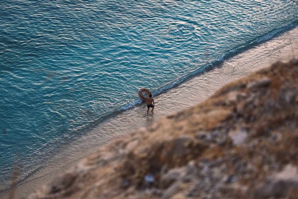 girl in black shirt and pants standing on rock by the sea during daytime