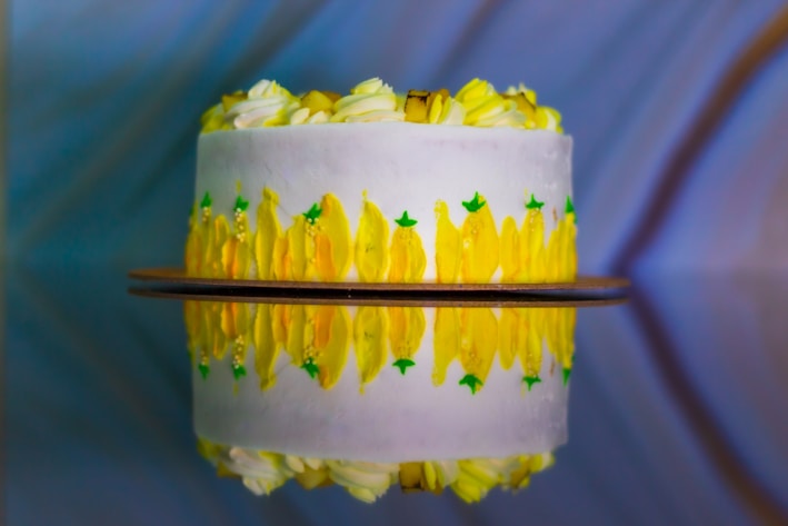 A vibrant yellow vanilla cake with smooth frosting and delicate decorations