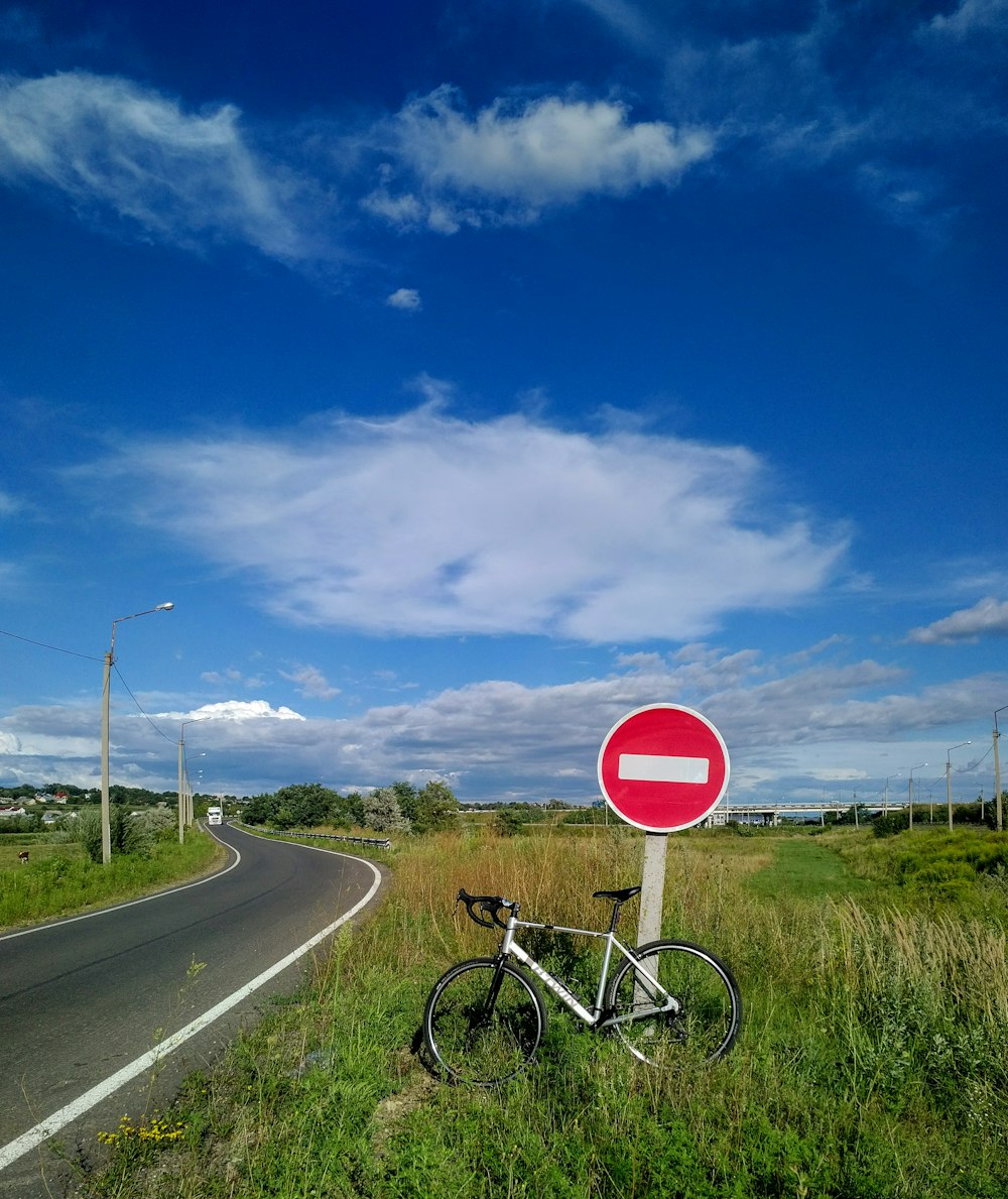 sinal de parada vermelho e branco no campo de grama verde sob o céu azul durante o dia