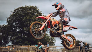 A close-up shot of a motocross rider mid-air over a dirt track under a moody sky.