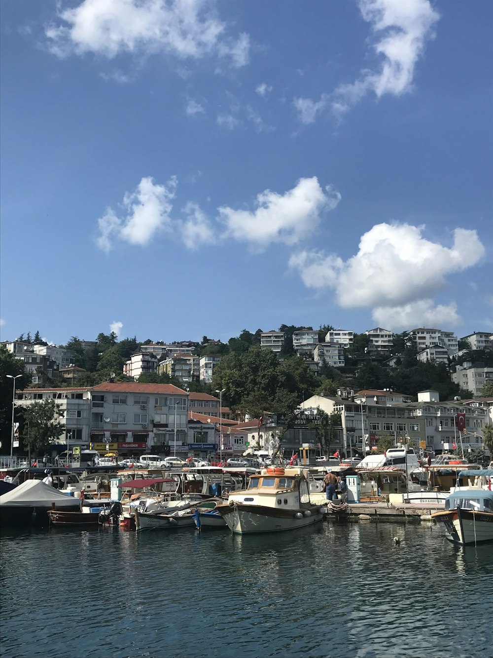 white and black boat on body of water near city buildings under blue and white sunny