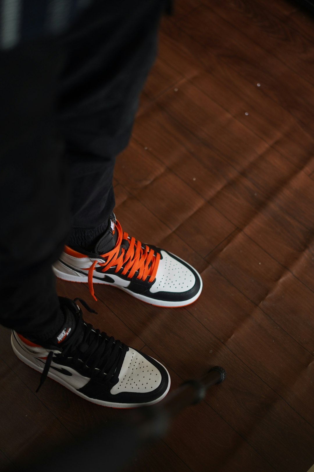 person in black pants wearing orange and white nike sneakers