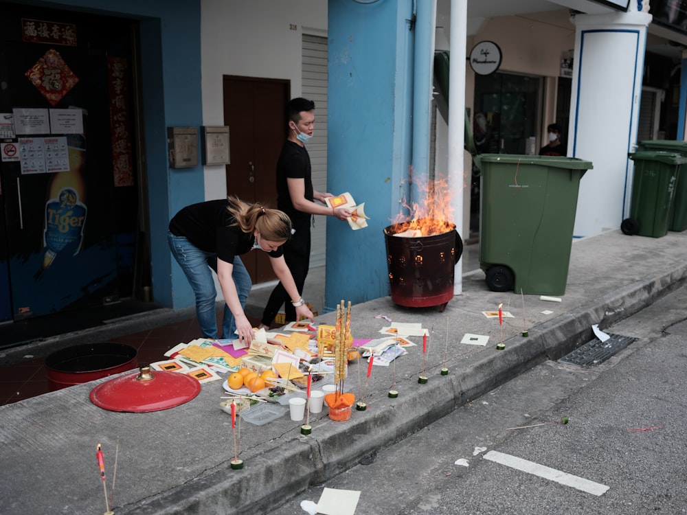 man in black t-shirt and blue denim jeans standing in front of fire pit