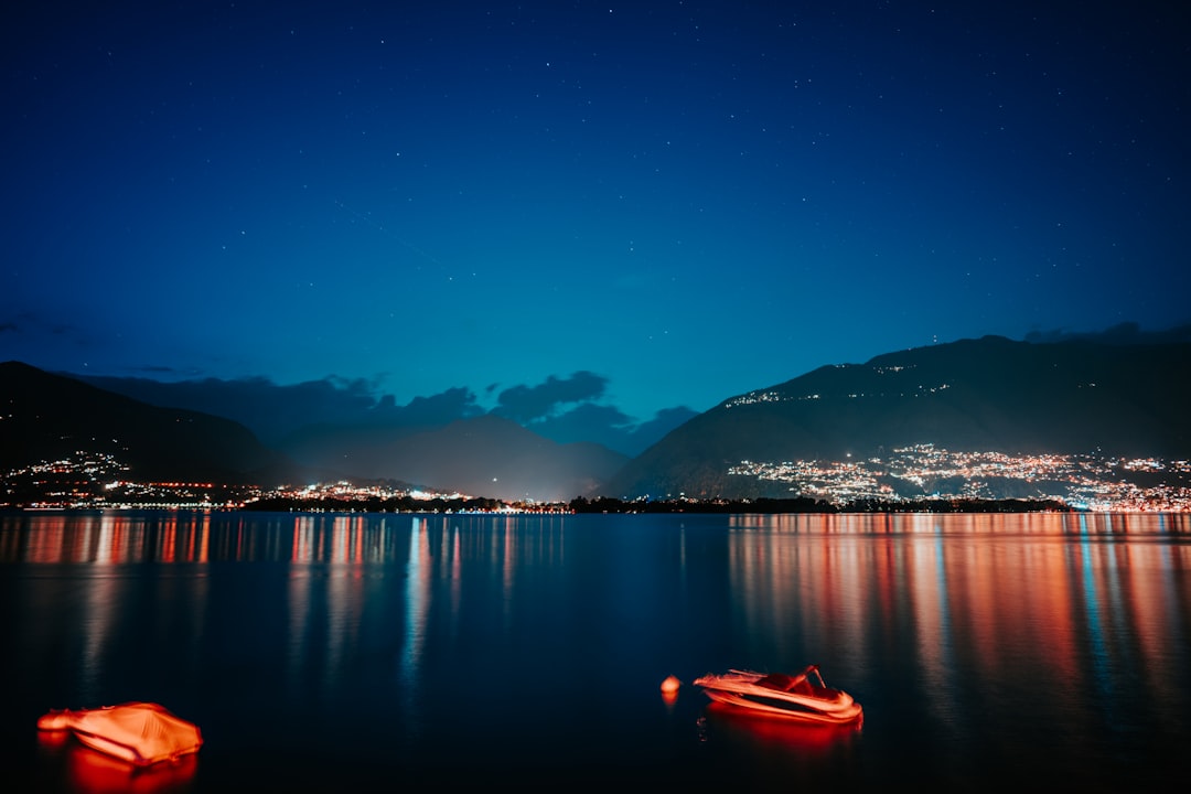 red kayak on calm water near mountain during night time