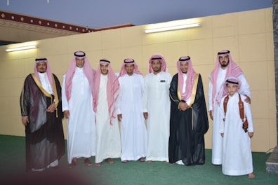 A group of men dressed in traditional Arabic thobes and ahram outdoors