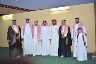 A group of men dressed in traditional Arabic thobes and ahram outdoors