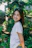A candid photo of Ella Green smiling in her lush vegetable garden during golden hour.