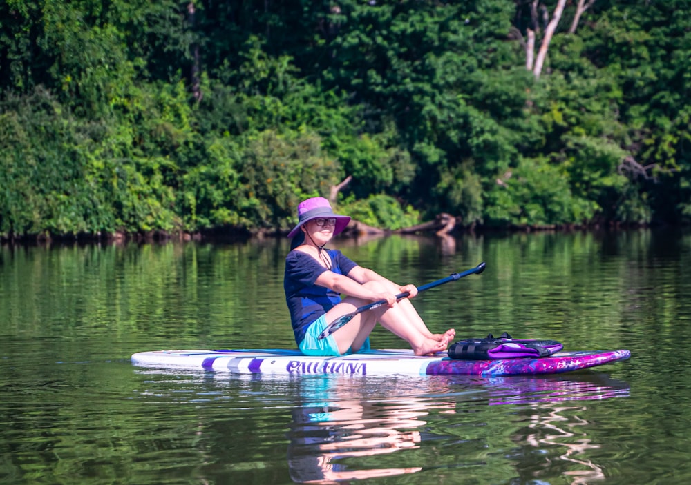 woman in blue and white life vest riding on blue kayak on river during daytime