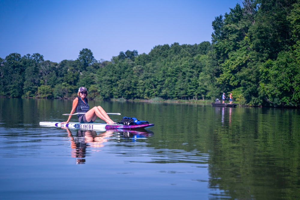 woman in pink bikini riding on blue kayak on lake during daytime