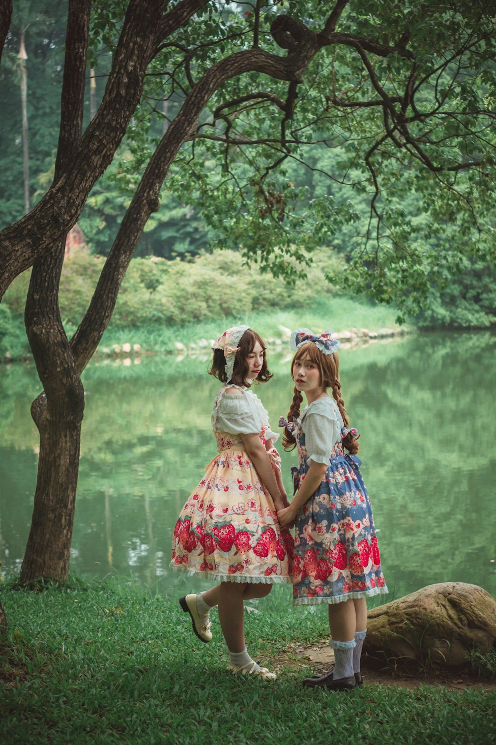2 girls standing beside tree during daytime