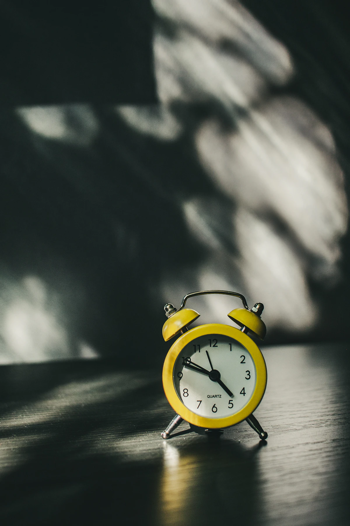 A small yellow analog alarm clock