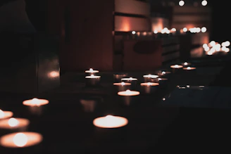 Softly lit candles arranged on a white linen cloth, highlighting their clean design and artisanal quality.