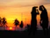 Golden hour shot of a couple laughing on deck, sails glowing softly behind them.