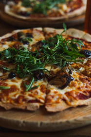 Artisan pizza topped with fresh vegetables and bubbling cheese on a wooden board.