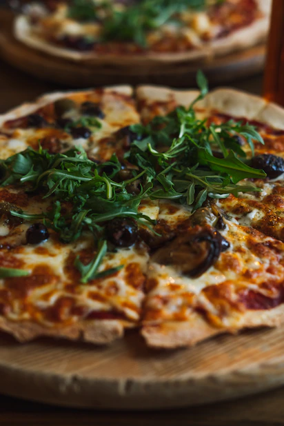 A freshly baked pizza with melted cheese, colorful veggies, and a golden crust on a rustic wooden board.