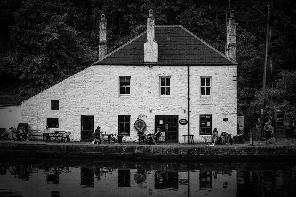 grayscale photo of house near body of water