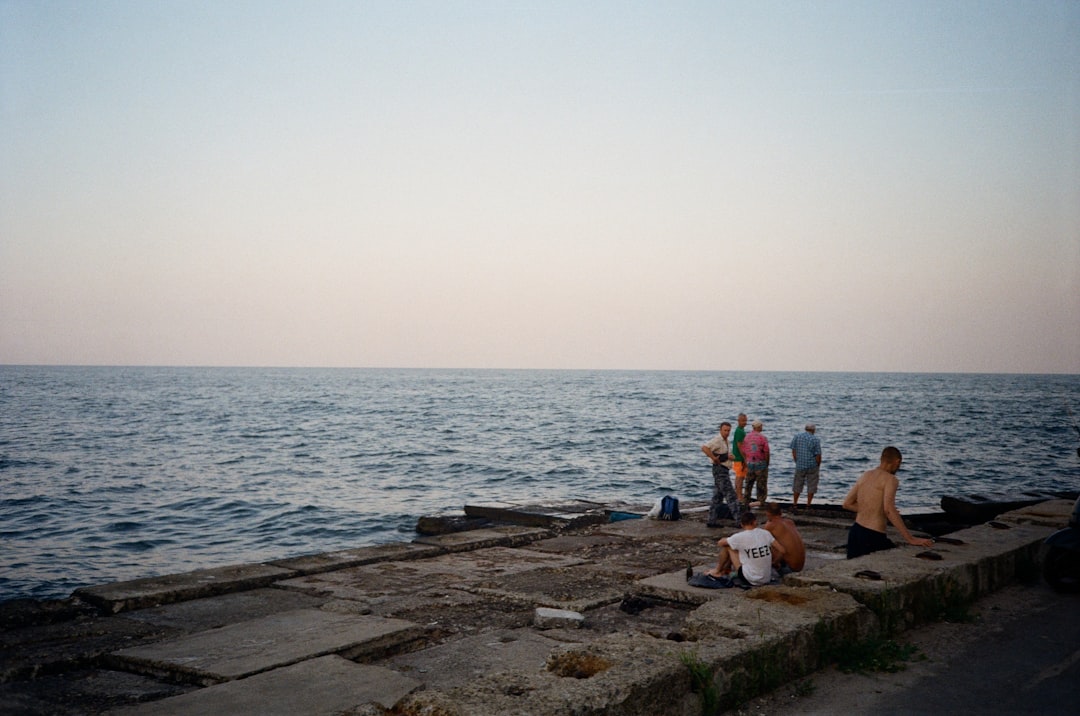 people sitting on brown wooden dock near body of water during daytime