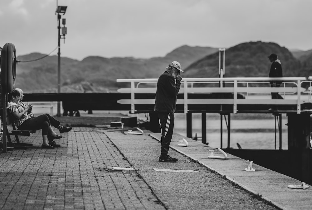 man in black jacket and pants walking on sidewalk during daytime